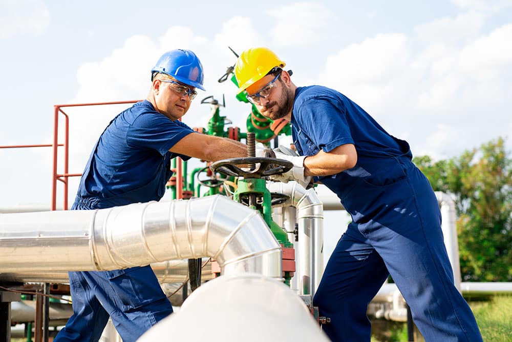 Two petrochemical workers inspecting pressure valves on a fuel